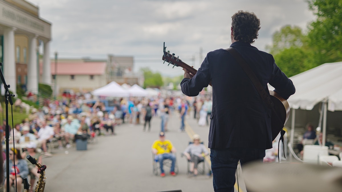 Siloutte of musician playing guitar to a crowd at the Trout Fest in Blue Ridge GA Fannin County